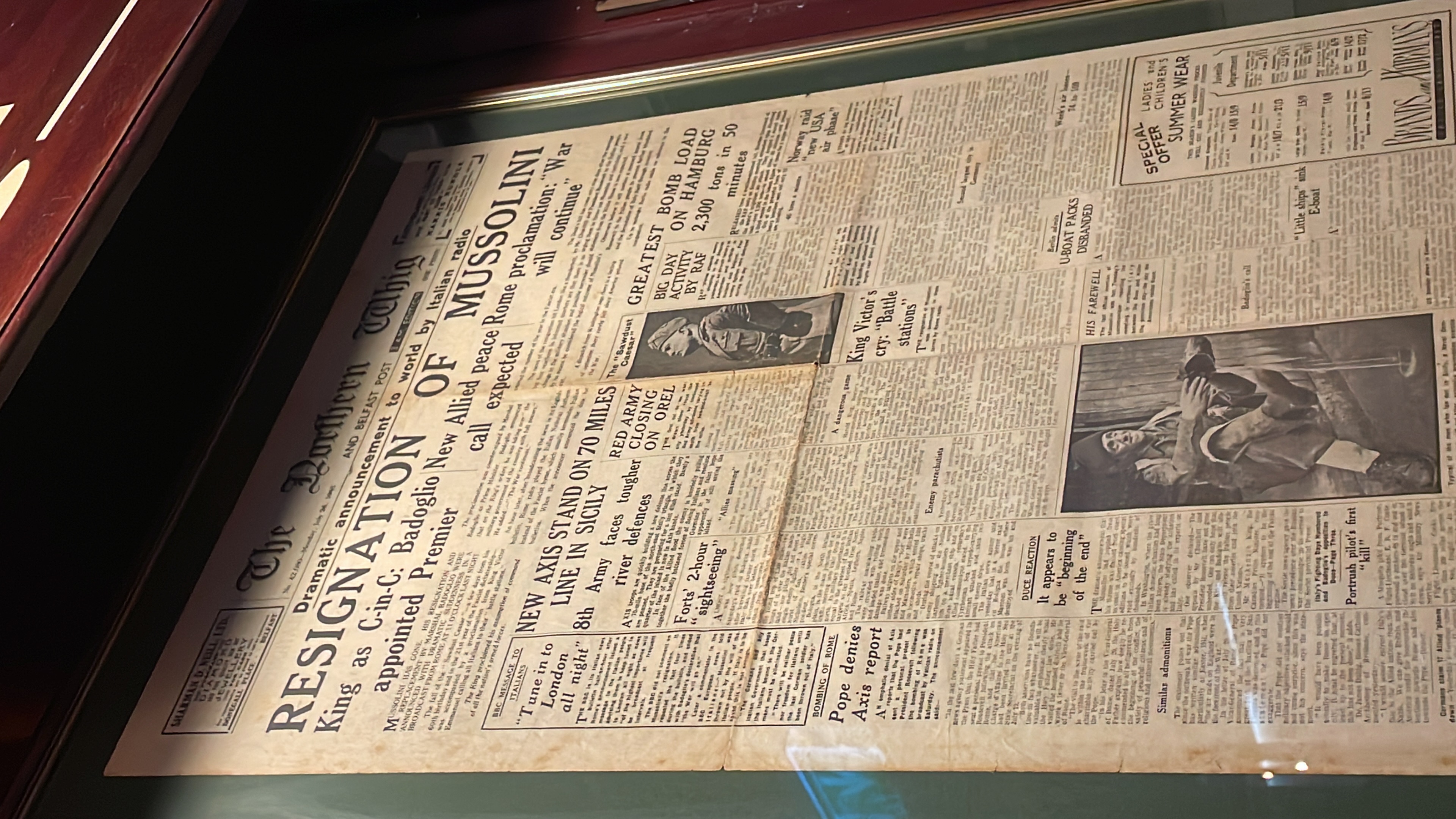 A newspaper front page in a frame reporting Mussolini's resignation